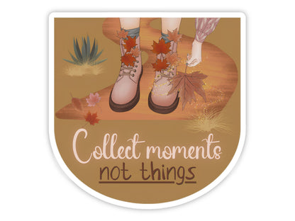 "Collect Moments, Not Things" slow living sticker. Pink lace-up boots on a golden desert path, a hand reaching for a fallen maple leaf, with agave and drifting autumn leaves