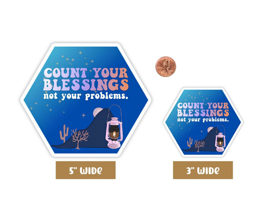 "Count Your Blessings, Not Your Problems" blessing sticker in 5-inch and 3-inch sizes with a penny for scale