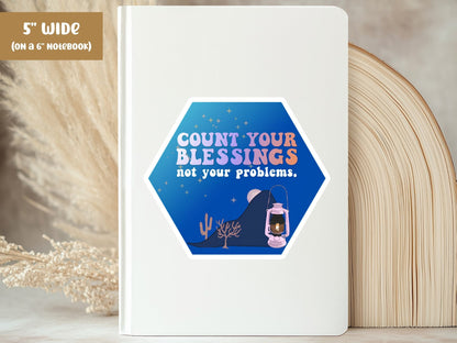 "Count Your Blessings, Not Your Problems" blessing sticker, 5-inch size, on the cover of a white 6-inch notebook