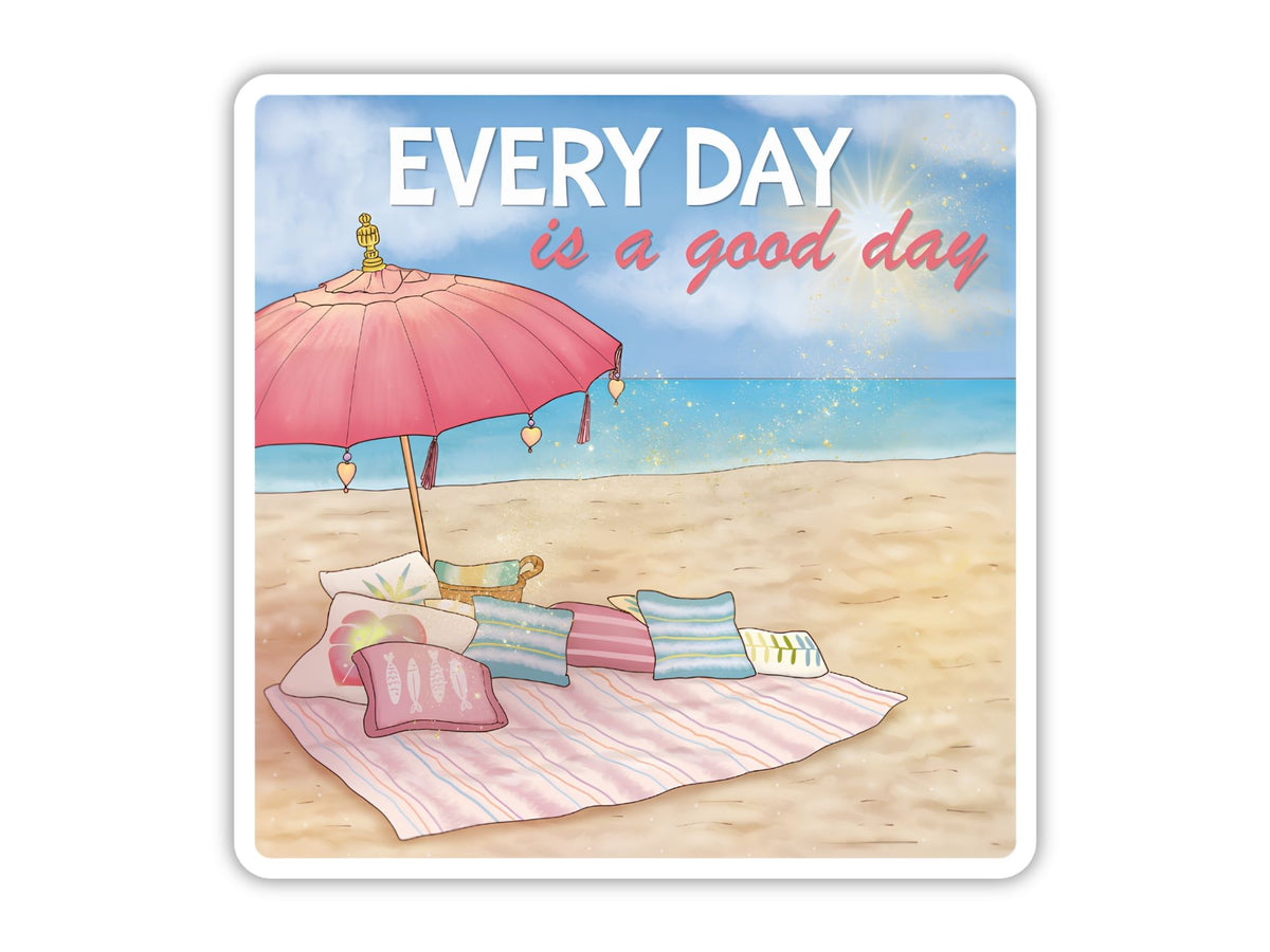 "Every Day is a Good Day" beach positivity sticker. A pink fringed umbrella over a striped beach blanket piled with pillows, with sparkling turquoise water and a bright sun